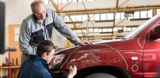 Dos hombres reparando un coche.

