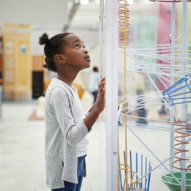 Una niña parada junto a una instalación científica creativa.